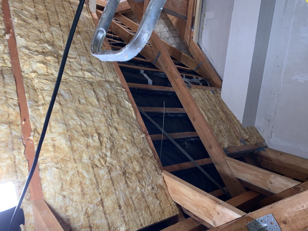 Dachdämmung mit Glaswolle zwischen den Holzsparren im Rohbau.